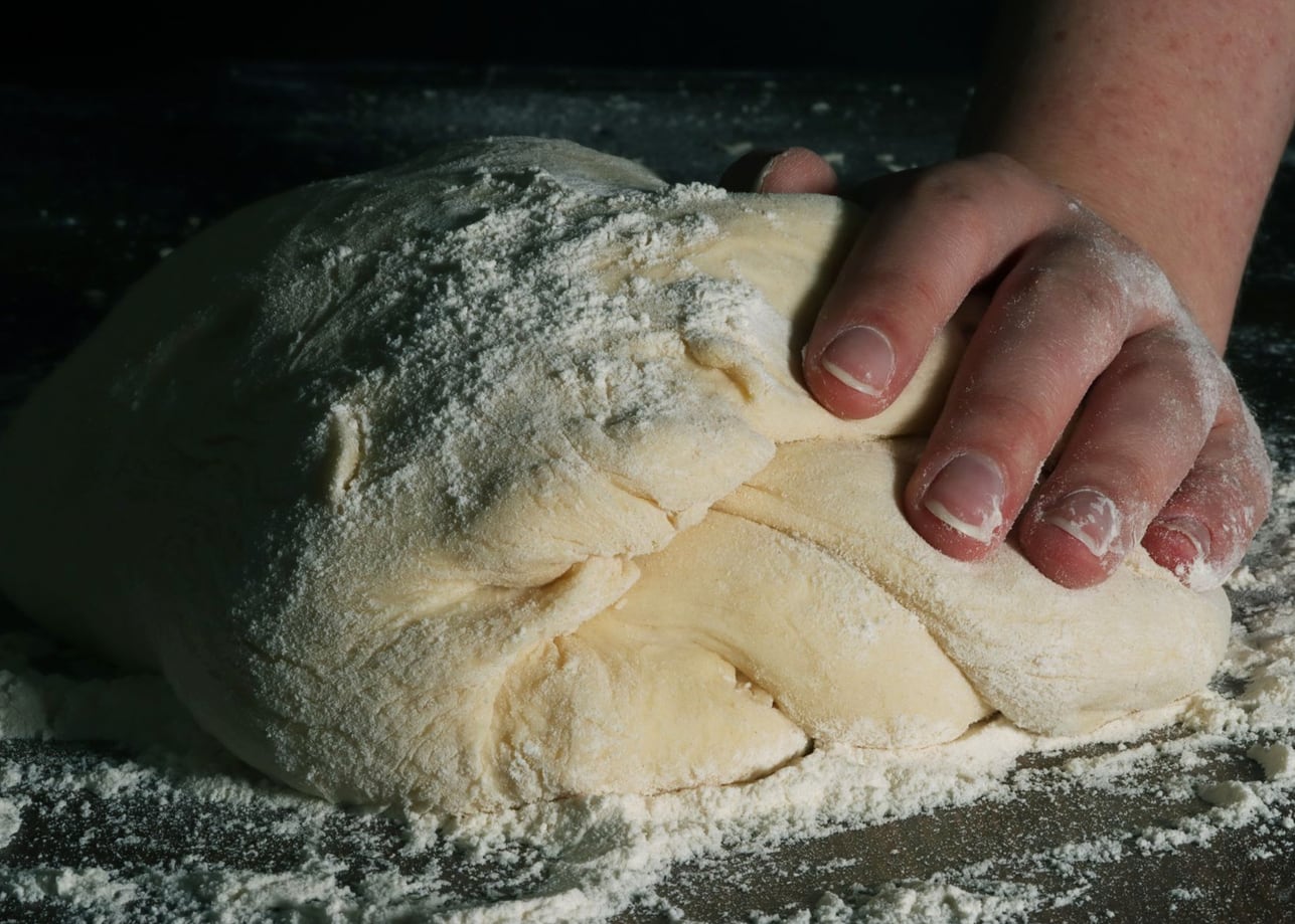 Massa de pão sendo trabalhada sobre a bancada da padaria